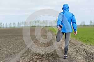 Running stretching - runner wearing smartwatch. Closeup of running shoes, woman stretching leg as warm-up before run.