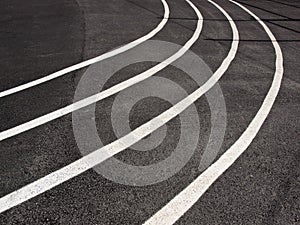Running track closeup with white curving lines painted on black