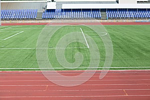 Running track and field with green grass for football at stadium.