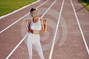 On the running track. Young woman in sportive clothes is exercising outdoors