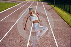 On the running track. Young woman in sportive clothes is exercising outdoors