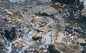 Running water of a mountain stream. Ice cold water and boulders