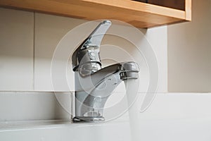 Running water tap, Interior of bathroom with sink basin faucet, Open chrome faucet washbasin.