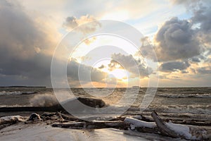 The running waves on the sandy snow-covered coast on a reservoir