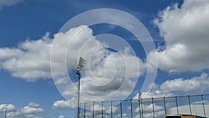 Running white clouds against the blue sky above the lighting mast. Accelerated video. Timelapse.