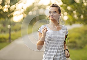 Running woman at the park in autumn season - Girl Runner Jogging Outdoor Workout - Young Female listening to music while jogging