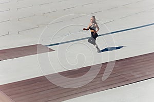 Running woman. Runner is jogging on sunrise. Female fitness model training outside in the city on a quay. Sport