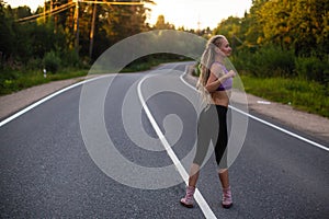 Running woman warms up before jogging on the suburban road. Sport.