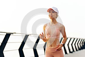 Running young woman, Runner runs in sunny bright light at sunrise, Female fitness model workout outside the city on the embankment