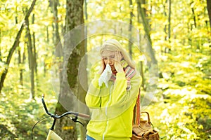 Runny nose remedies. Woman handkerchief sneezing because of allergy. Blonde allergic reaction relax forest. Girl bicycle