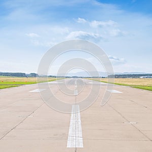 Runway at the airport in sunny summer noon with clouds