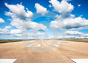 Runway, airstrip in the airport terminal with marking on blue sky with clouds background. Travel aviation concept...