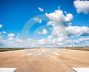 Runway, airstrip in the airport terminal with marking on blue sky with clouds background. Travel aviation concept...