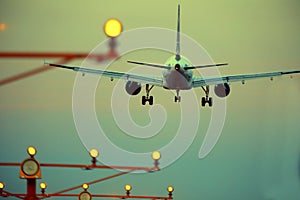 Silhouette of plane landing, runway lights, orange effect