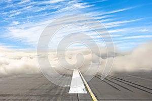 Runway road wrapped in dense low fog, clear blue sky from above. The concept of bad weather at the airport, the delay in the