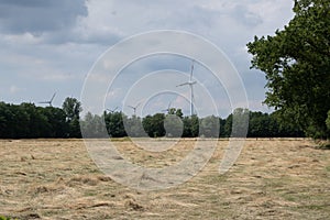 Rural agricultural field with wind turbines under a cloudy dark sky