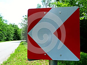 Rural asphalt road with sharp curve and red and white road side arrow