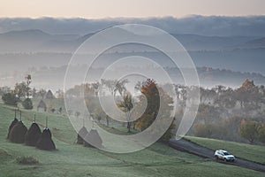 rural autumn landscape with fog and hay stacks