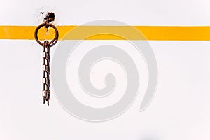 Rural background of a rusty ring on a white wall with orange line to tie animals