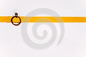 Rural background of a rusty ring on a white wall with orange line to tie animals