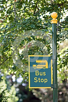 Rural bus stop sign in close-up. Yellow and green post.