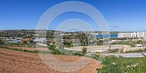 Rural countryside of Malta with dry crop fields, plowed land and blue water of the mediterranean sea bay