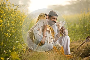 Rural couple holding Indian rupee notes in agriculture field