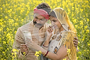 Rural couple holding Indian rupee notes in agriculture field