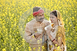 Rural couple holding Indian rupee notes in agriculture field