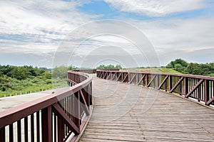 Rural curving planked steel bridge in cloudy summer afternoon