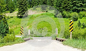 Rural dirt road crossing a narrow wooden bridge