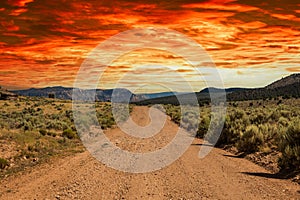 A rural dirt road leading off to distant mountains