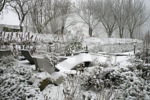 The rural garden in winter clothes. Garden furniture covered with snow in cloudy winter day.