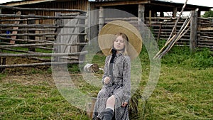 Rural girl with curly hat posing on rural landscape in countryside. Romantic countrygirl in hat and dress posing on