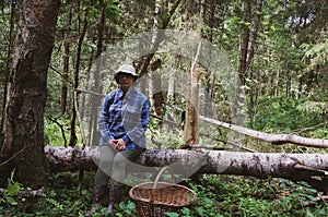 Rural girl mushroom picker with a basket sitting on a broken birch