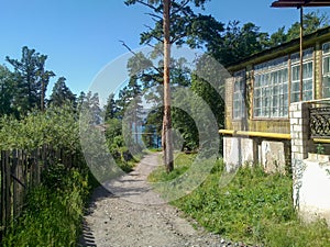 Rural house and garden fences by the dirt road on a beautiful sunny day in Russia