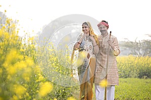 Rural indian couple standing in rapeseed field