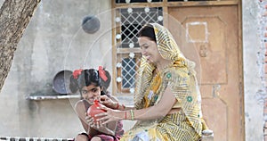 Rural Indian woman with daughter holding piggy bank