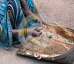 A rural Indian woman rolls tobacco cigarettes