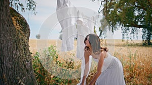 Rural lady correcting laundry rope at summer field. Country girl putting basket