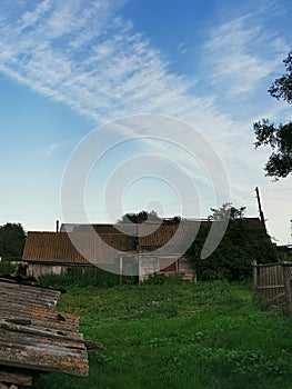 Rural landscape with abandoned wooden house, sky and meadow