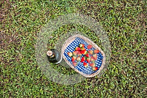 Rural landscape and blue and white napkin brown basket with strawberry and bottle of wine. Top view