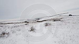 Rural landscape of fields and meadows covered with snow in winter, view from an FPV drone. Drone racing, fun modern