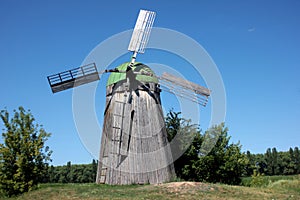 Rural landscape with Old wooden windmill on the blue sky background in summer day.