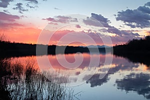 Rural landscape with river and mountain during colorful sunset with clouds