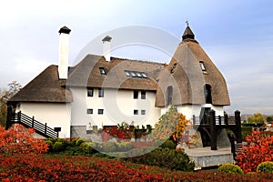 Rural landscape. Thatched roof house in autumn. Cottage in rustic style in leaf fall. Tourism in countryside. Dnipro, Ukraine