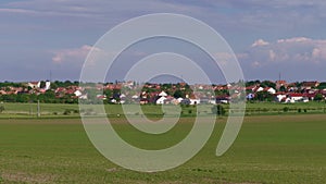 Rural landscape, town houses, walking people, green field