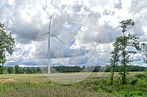 Rural landscape with wind turbine, windmill  for electric power production  - closeup, sky with stormy clouds in the background.