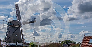 Rural landscape with a windmill and houses against a cloudy sky