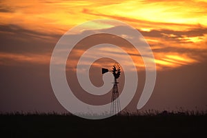 Rural landscape with windmill at sunset